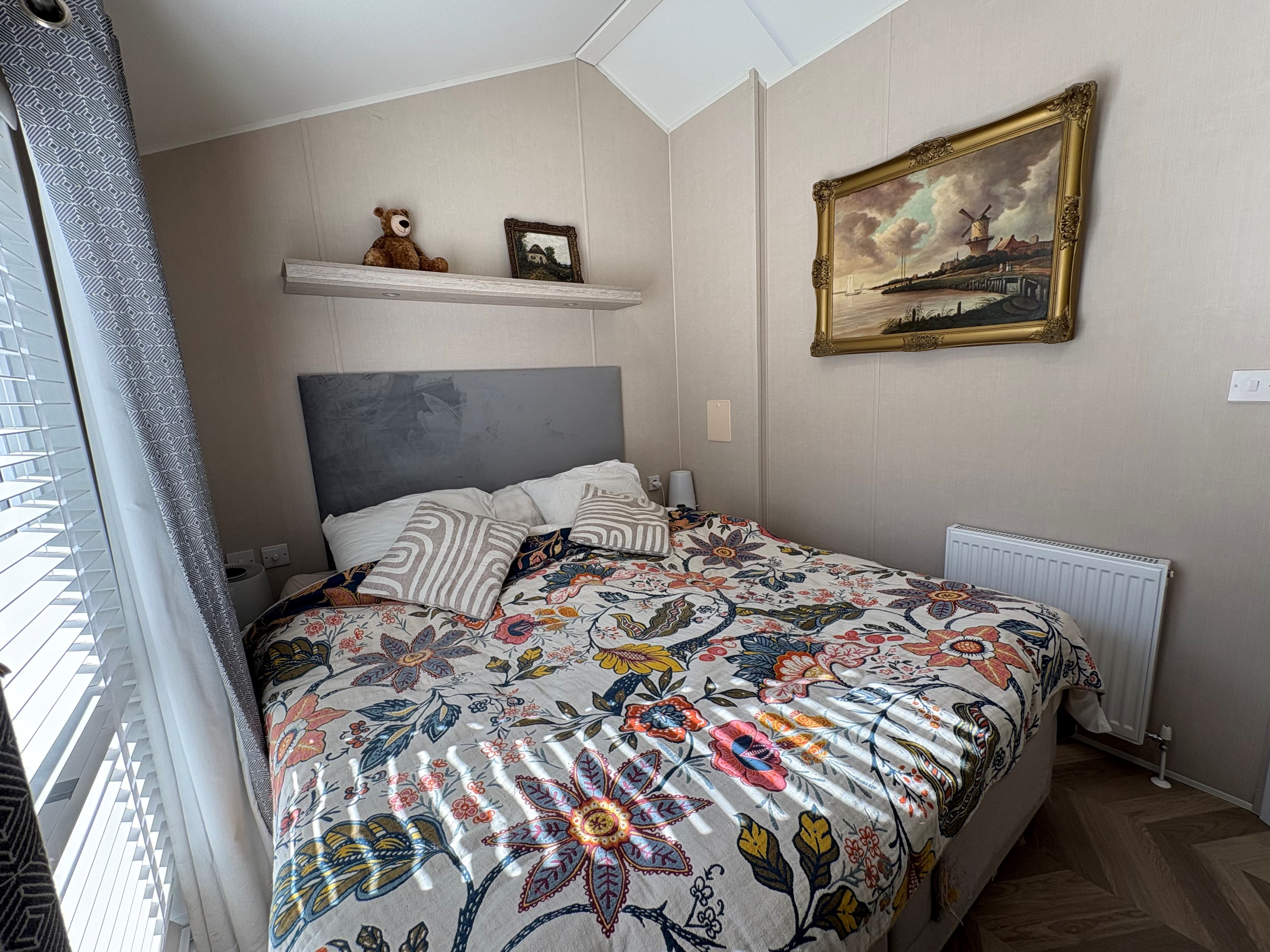 Sfeervolle slaapkamer met een grootbed, kleurrijk dekbedovertrek en een schilderij aan de wand