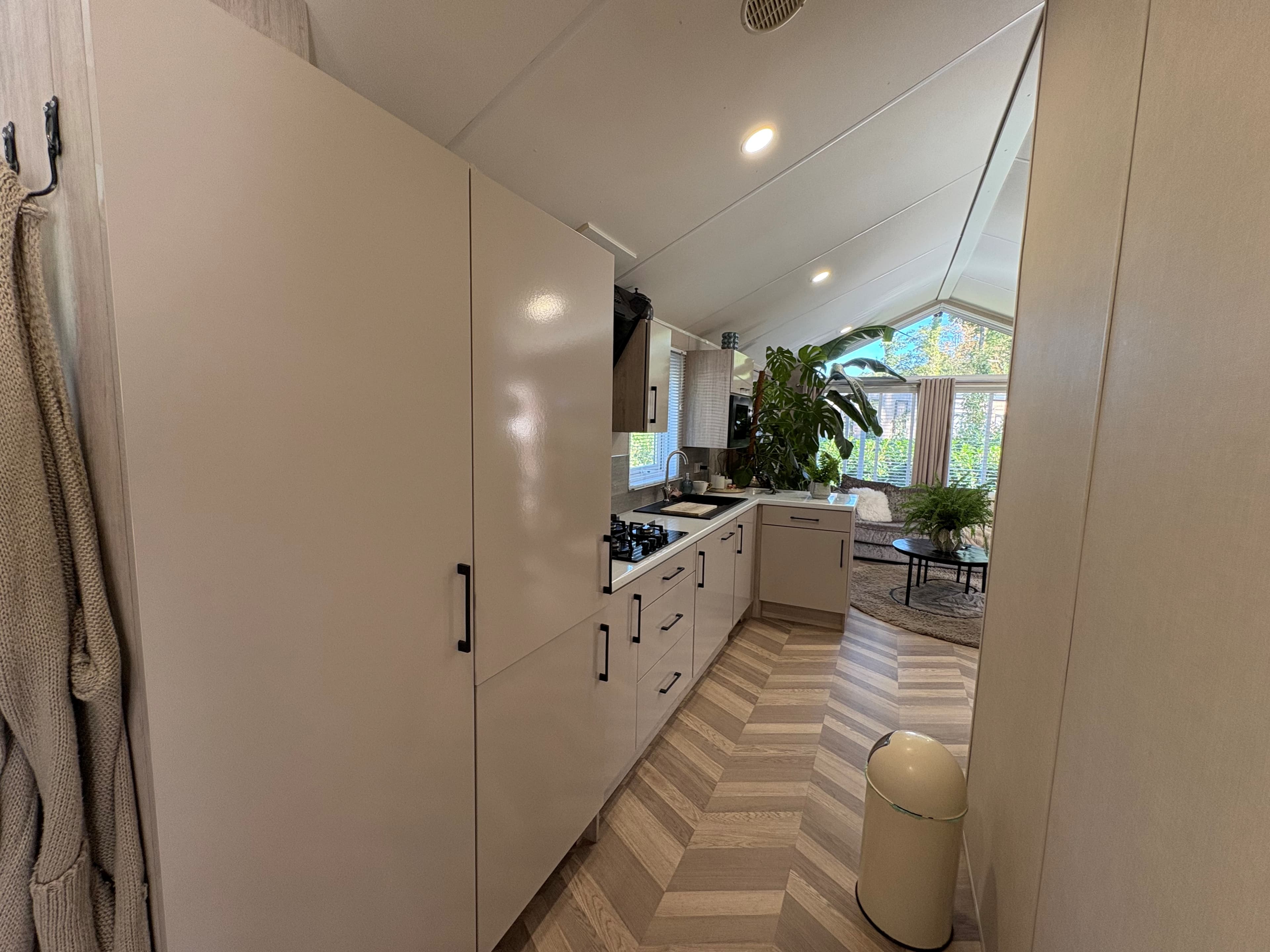 Keuken in recreatiewoning met moderne kasten, gasfornuis en een grote plant bij een raam voor natuurlijk licht