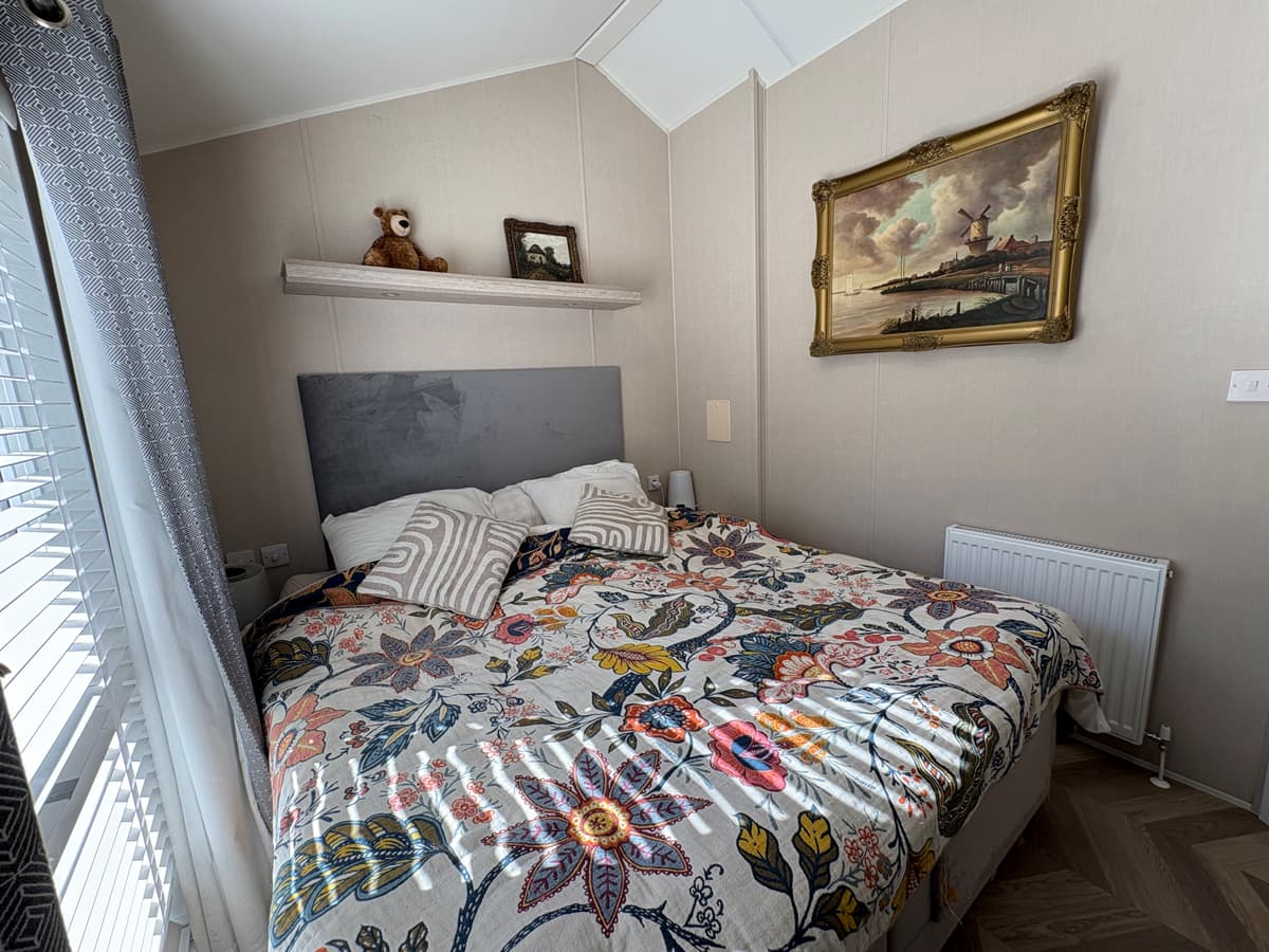 Sfeervolle slaapkamer met een grootbed, kleurrijk dekbedovertrek en een schilderij aan de wand