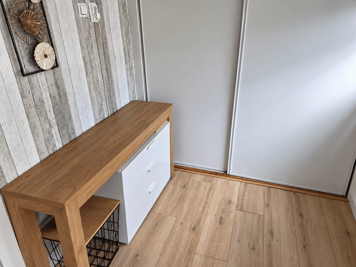 Ingang van de recreatiewoning met een houten kast en een wanddecoratie van hout en schijfjes aan de muur