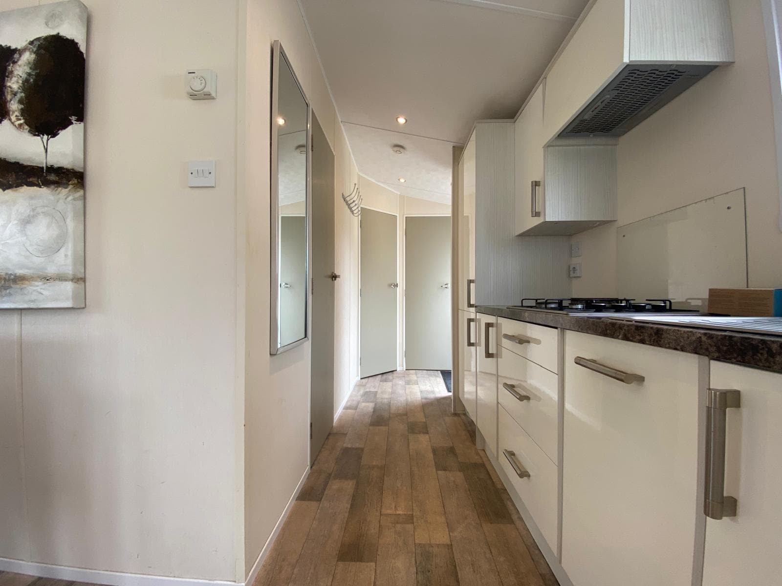Moderne keuken met kastruimte en kookplaat, zicht op gang met deuren naar slaapkamers.