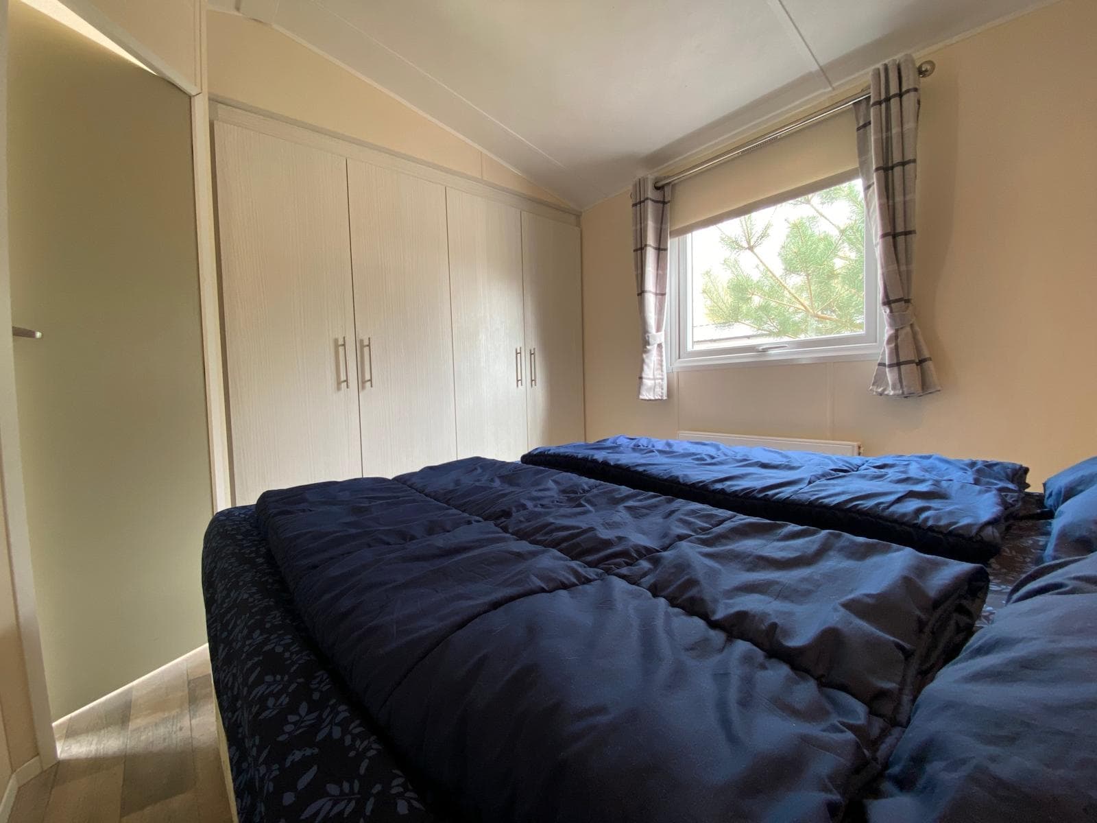 Slaapkamer met twee eenpersoonsbedden en een kledingkast, raam met uitzicht op buiten.
