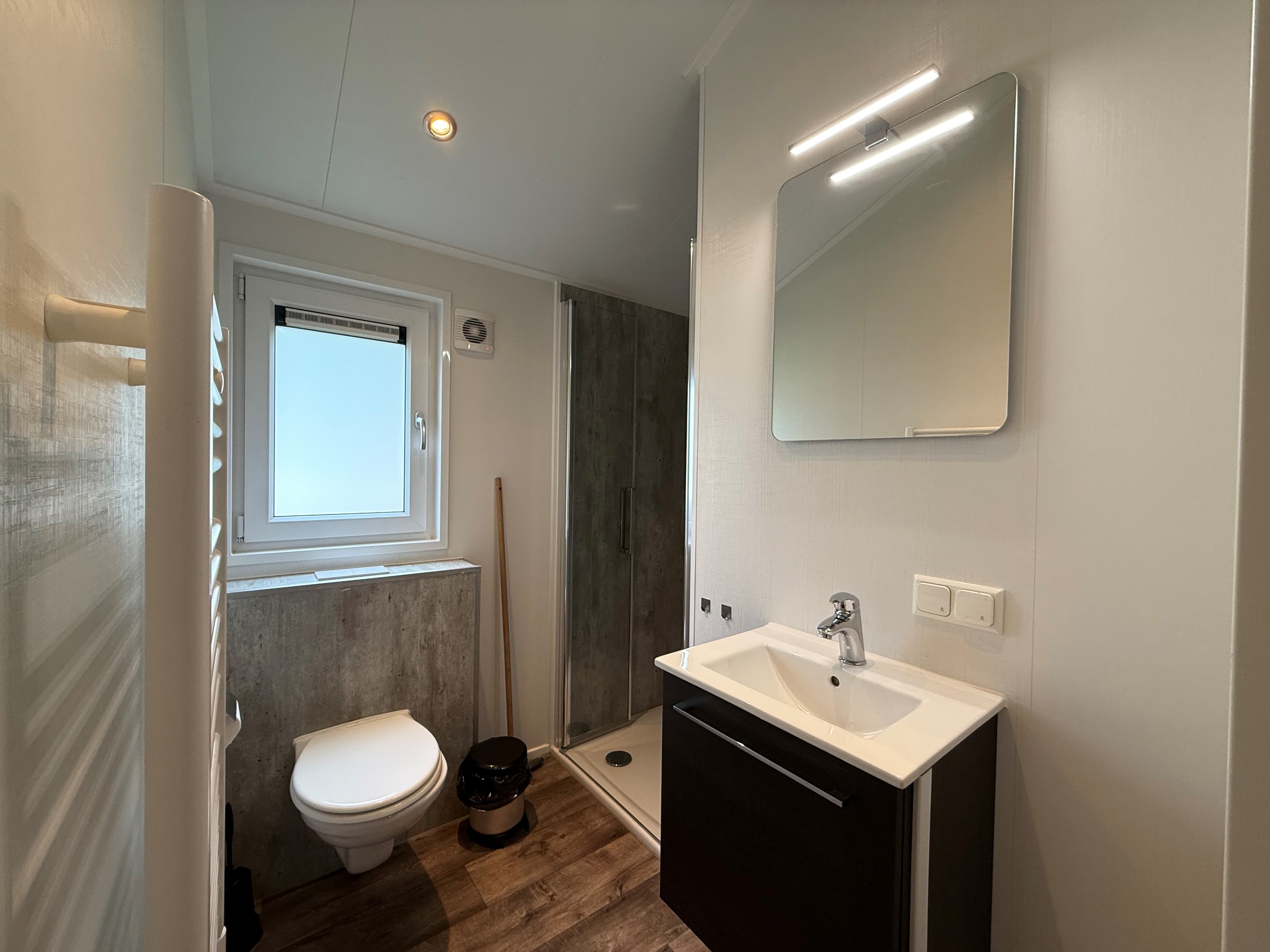 Netjes badkamer met douche, toilet, wastafel en spiegel, lichte kleuren en raam voor natuurlijk licht
