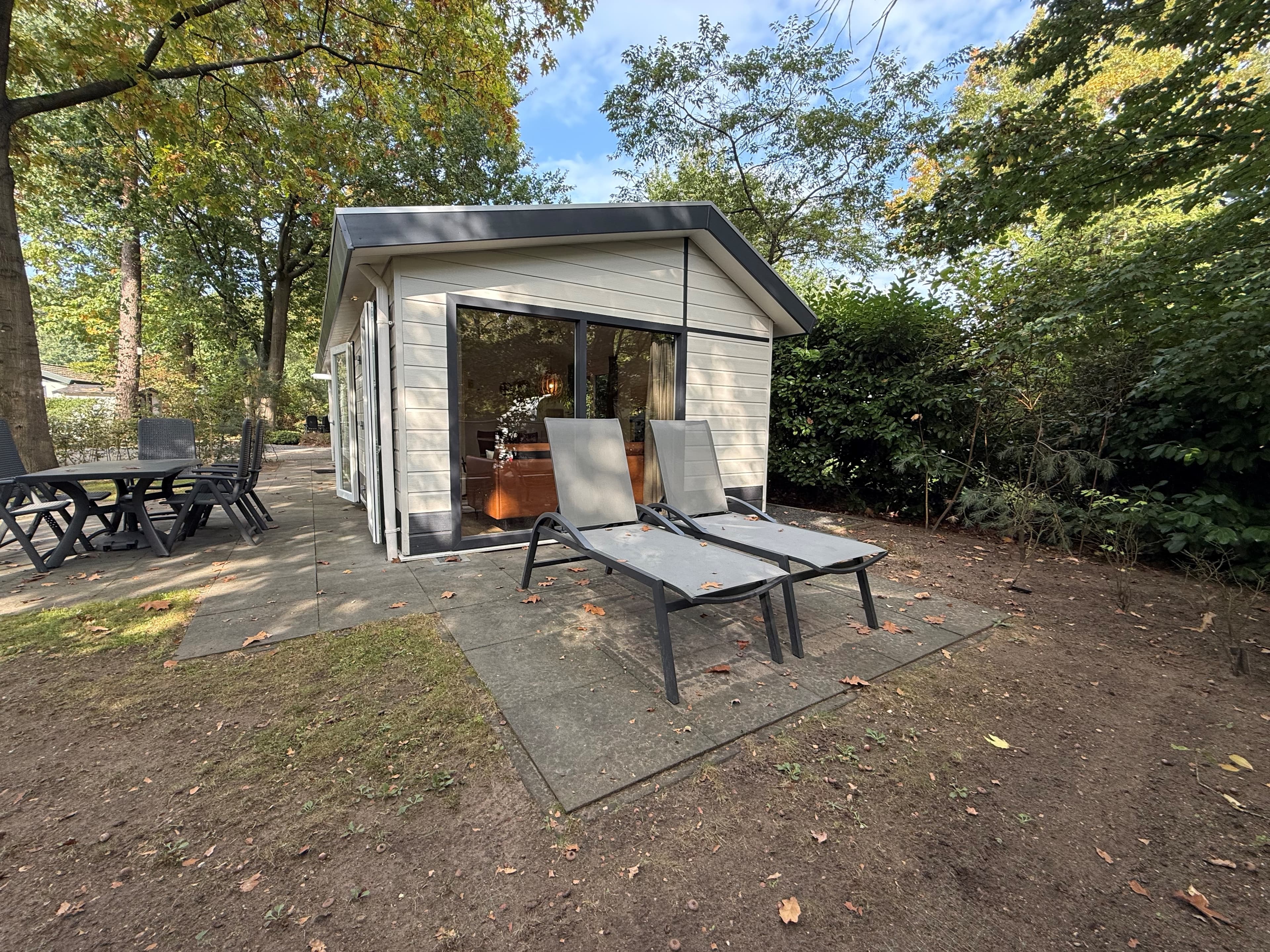 Recreatiewoning met terras, zitstoelen en uitzicht op groene omgeving en bomen rondom