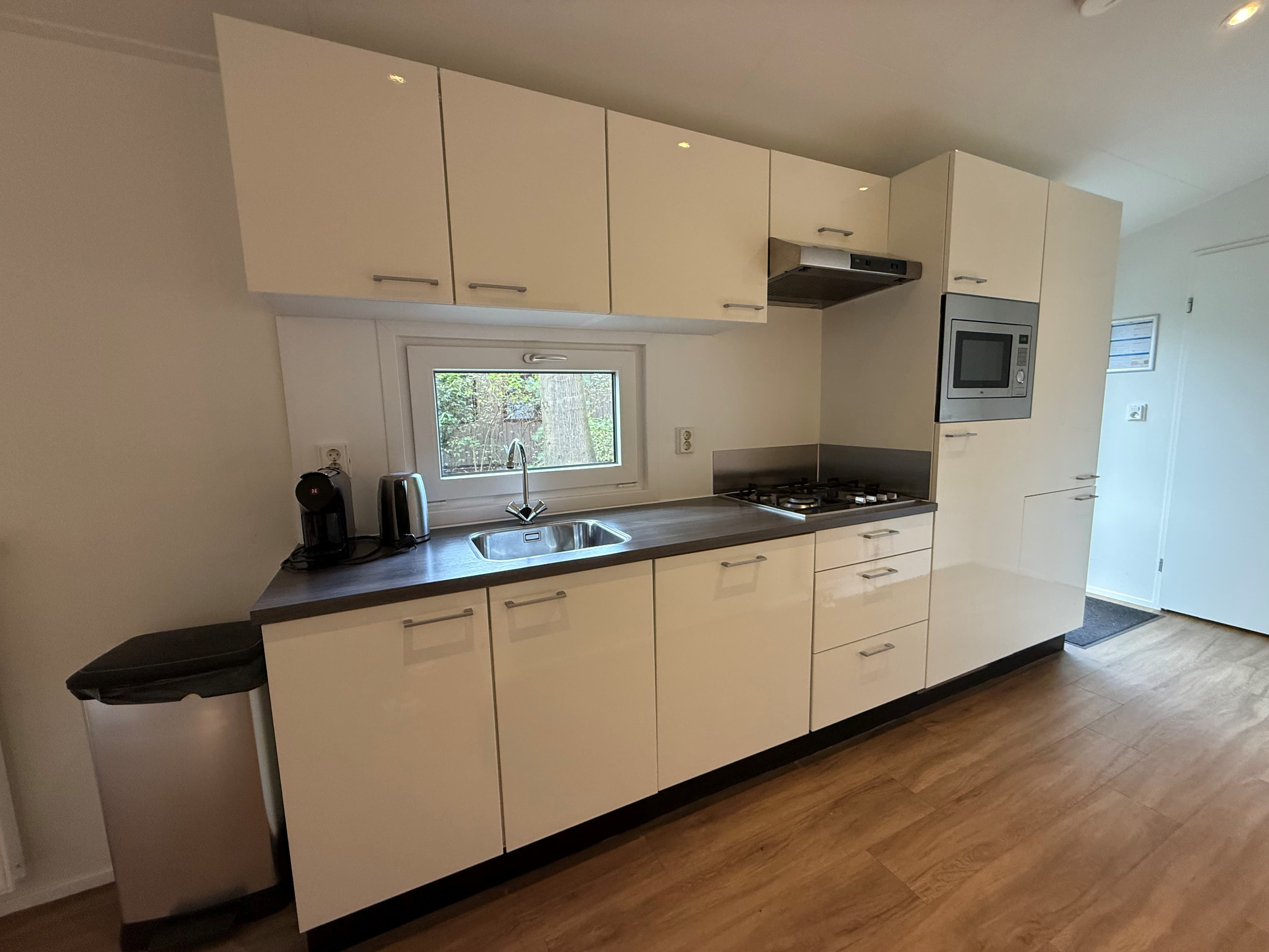 Moderne keuken met witte kasten, apparatuur, spoelbak en veel opbergruimte in een recreatiewoning.