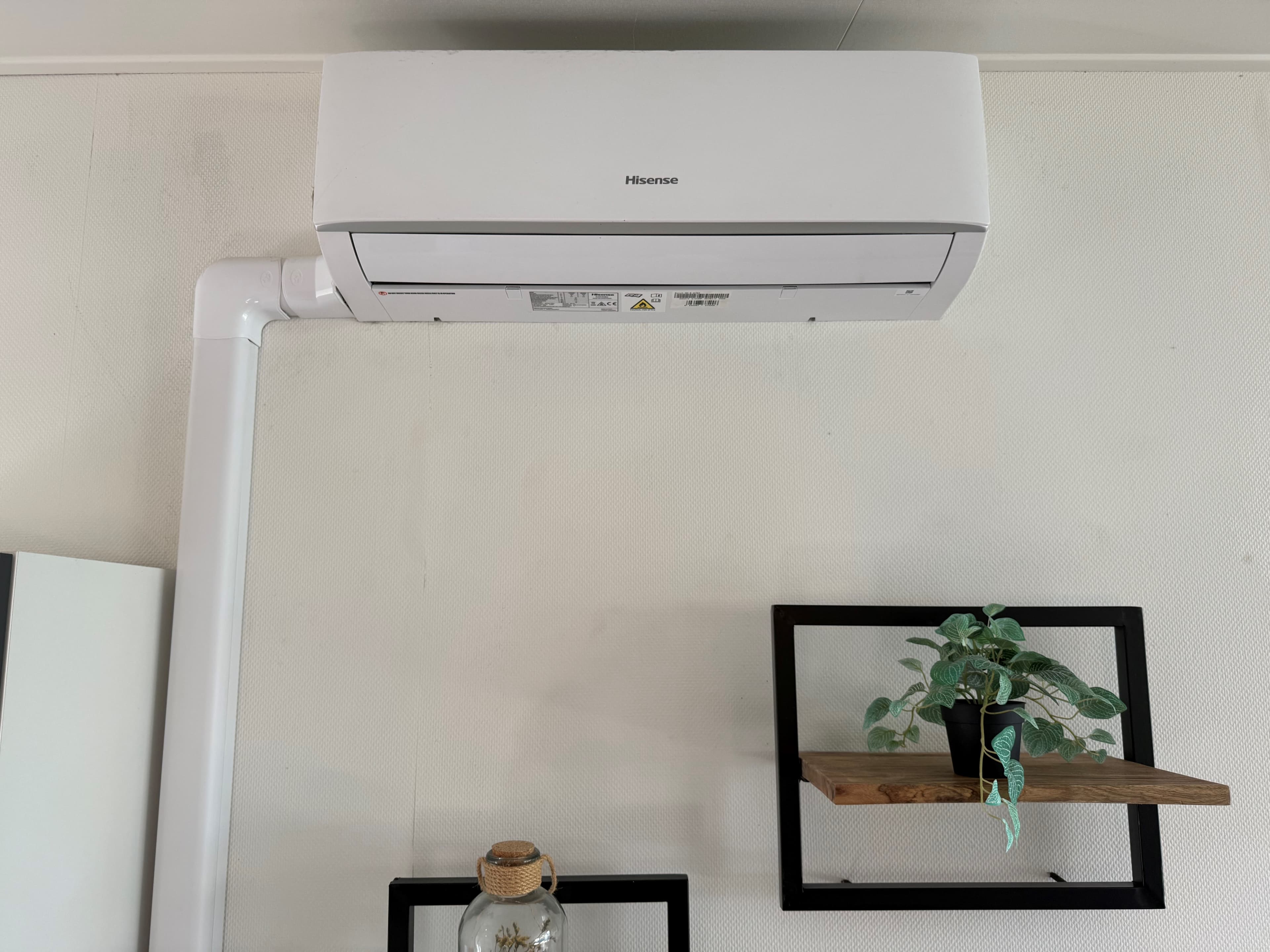 Wandairconditioner aan het plafond met een plankje en plantjes aan de muur