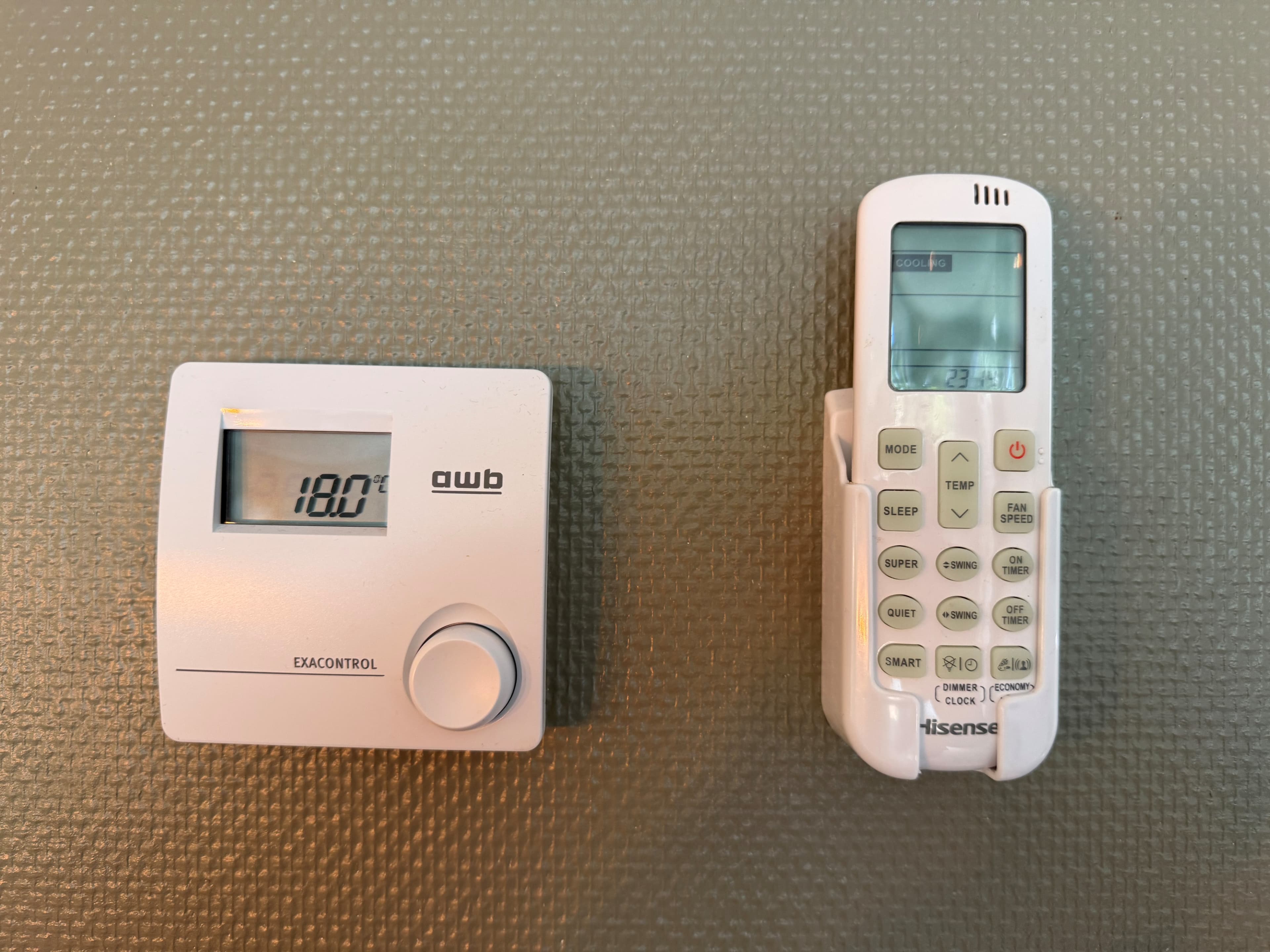 Thermostaat en afstandsbediening voor airconditioning op een wand met een stijlvolle textuur