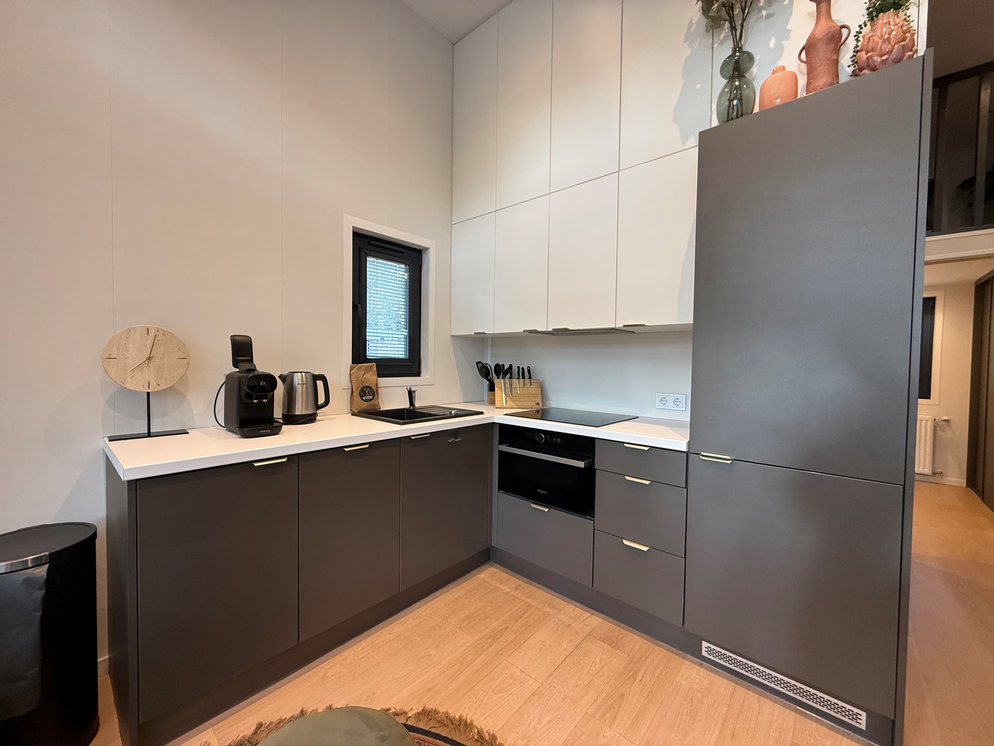 Moderne keuken met grijze en witte kastjes, inbouwapparatuur en een minimalistische inrichting.