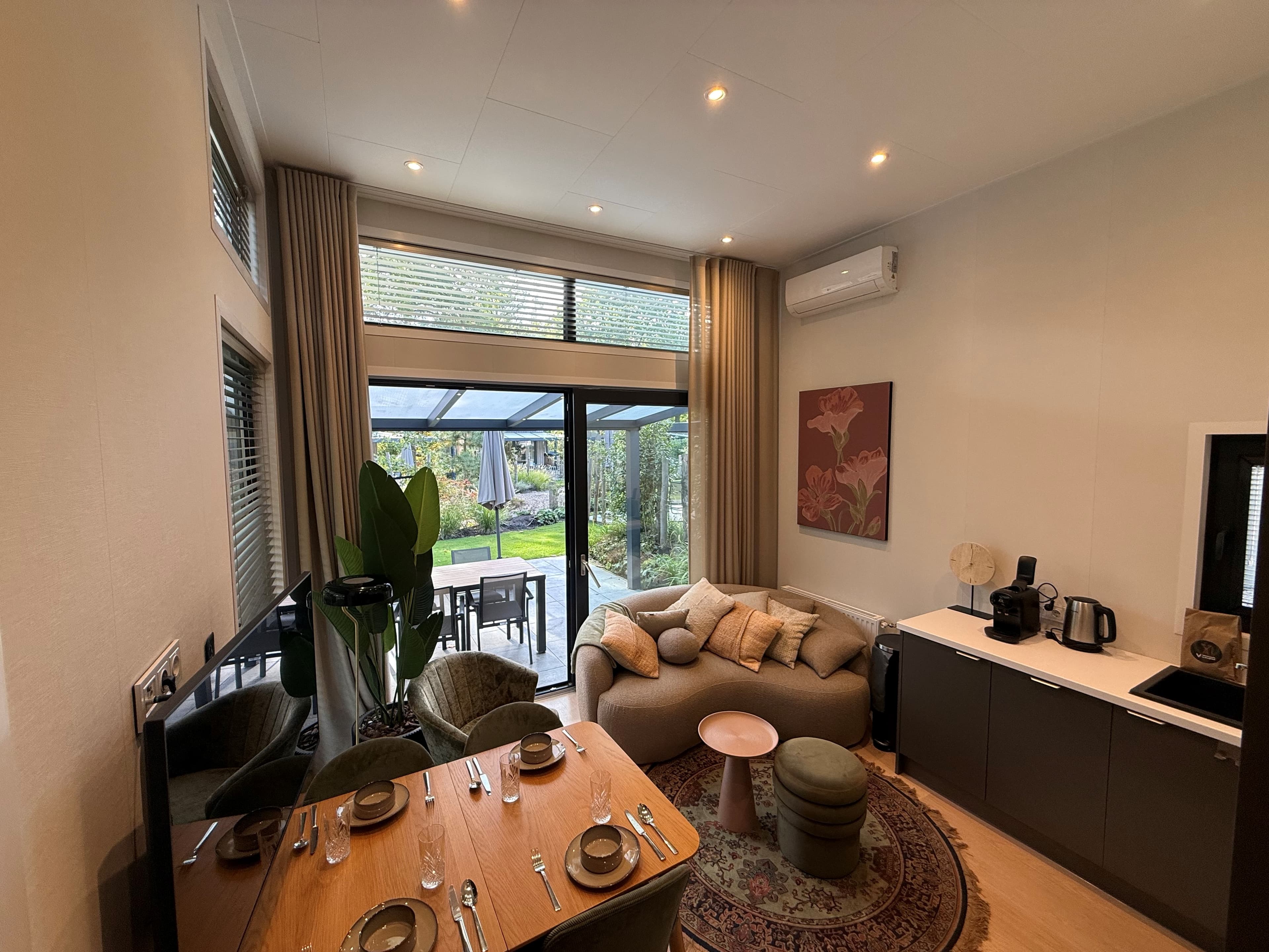 Woonkamer met zithoek, eettafel en toegang tot tuin met terras en groene omgeving