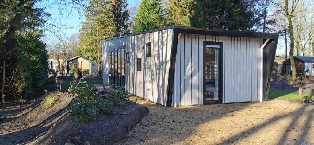 Moderne vakantiewoning met houten gevel en grote ramen, omgeven door groen en aangelegde tuin in EuroParcs Zuiderzee.