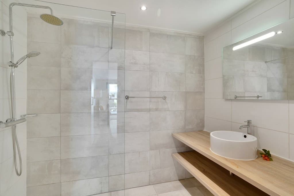 Moderne badkamer met inloopdouche, wastafel op houten plank en grote spiegel aan de wand