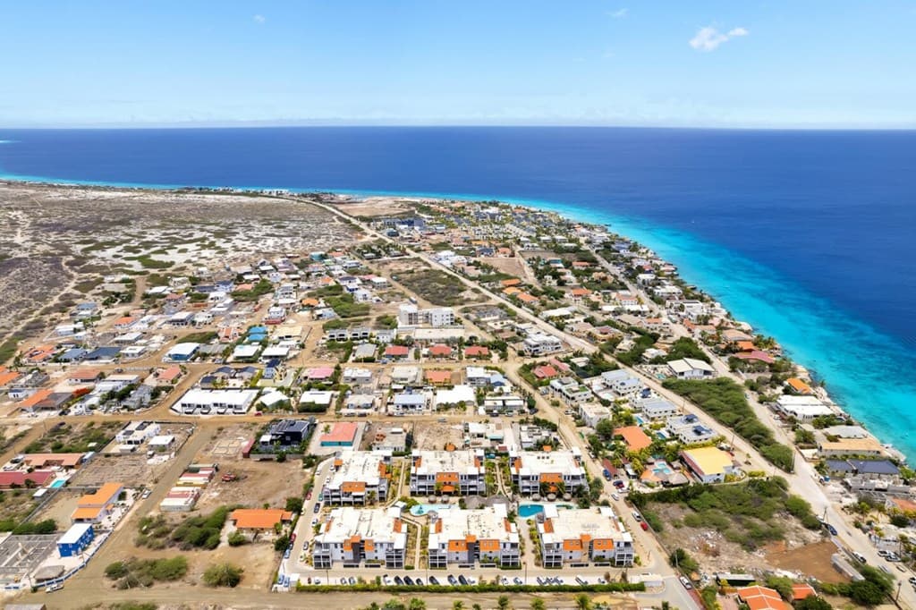 Luchtfoto van Kralendijk met het Delfins Beach Resort en turquoise zee op de achtergrond