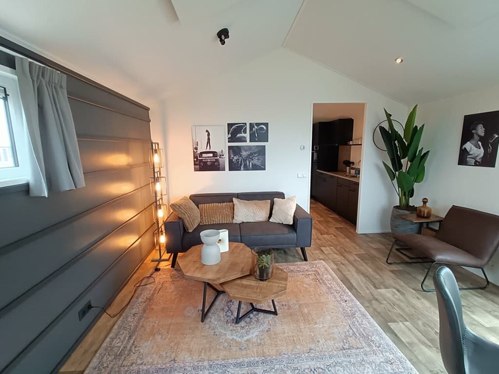 Gezellige woonkamer met bank, salontafel en kunst aan de muur, met toegang tot de keuken in de achtergrond.
