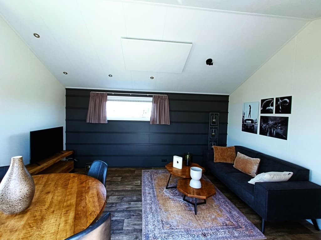 Ruime woonkamer met een zithoek, eettafel en moderne decoratie, voorzien van raam met uitzicht en kunst aan de muur
