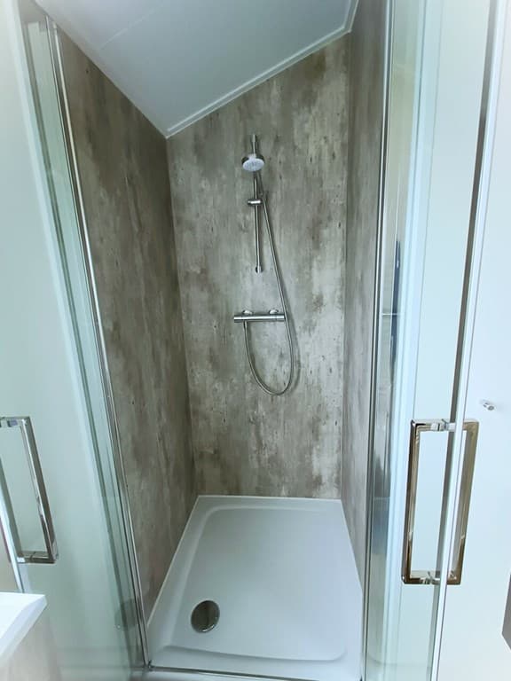 Moderne inloopdouche met glazen wand en regendouchekop, in een neutrale kleurstelling.
