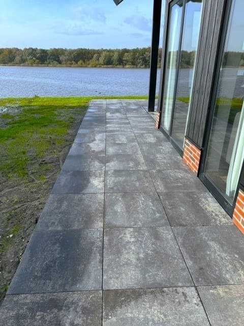 Terras met grote tegels en uitzicht op water en groene omgeving bij EuroParcs De IJssel Eilanden in Kampen