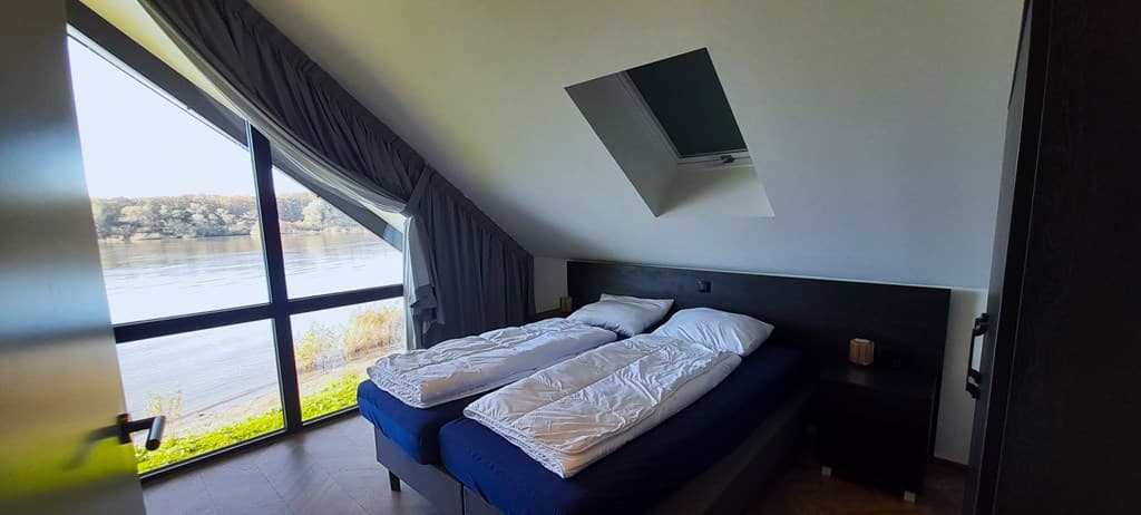 Slaapkamer met twee aparte bedden en uitzicht op het water door grote ramen
