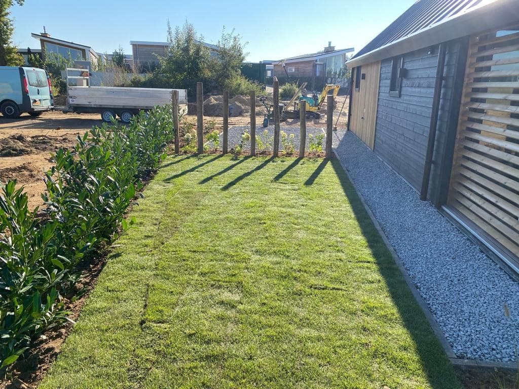 Groene tuin met gras en hagen, bestrating en houten schutting bij een woning in Green Resort Mooi Bemelen