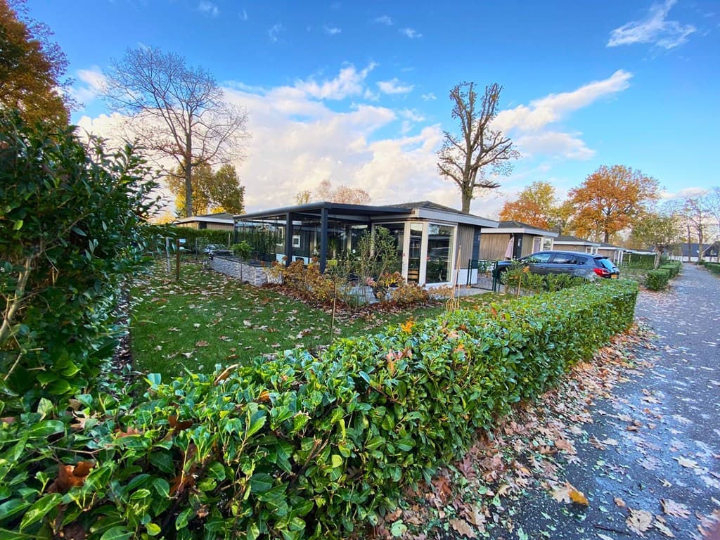 Vakantiewoning met een groene tuin en een terras, omringd door hagen en bomen, gelegen in EuroParcs Limburg.