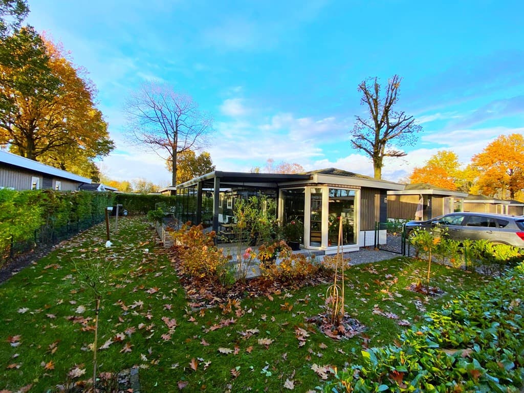 Moderne vakantiewoning met een terras, omringd door groen en herfstbladeren in EuroParcs Limburg.