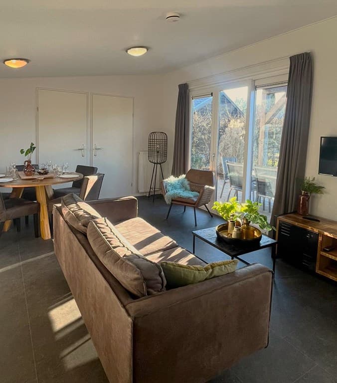 Moderne woonkamer met zithoek, eettafel en toegang tot terras met veel lichtinval en plantendecoratie