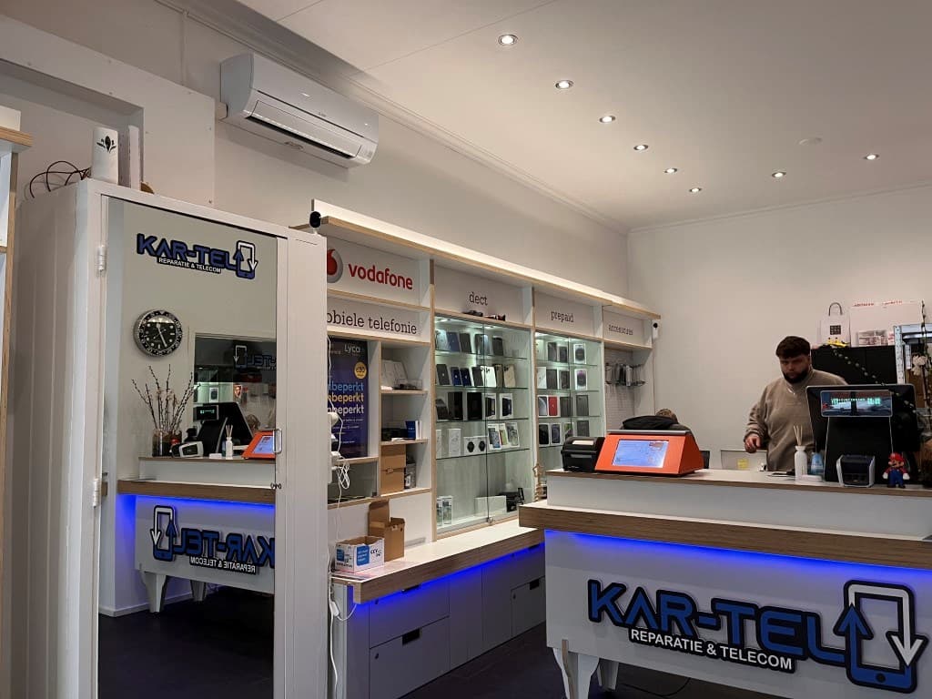 Interieur van een winkel met accessoires voor mobiele telefoons en een serviceteller, medewerkers aan het werk en displays ac