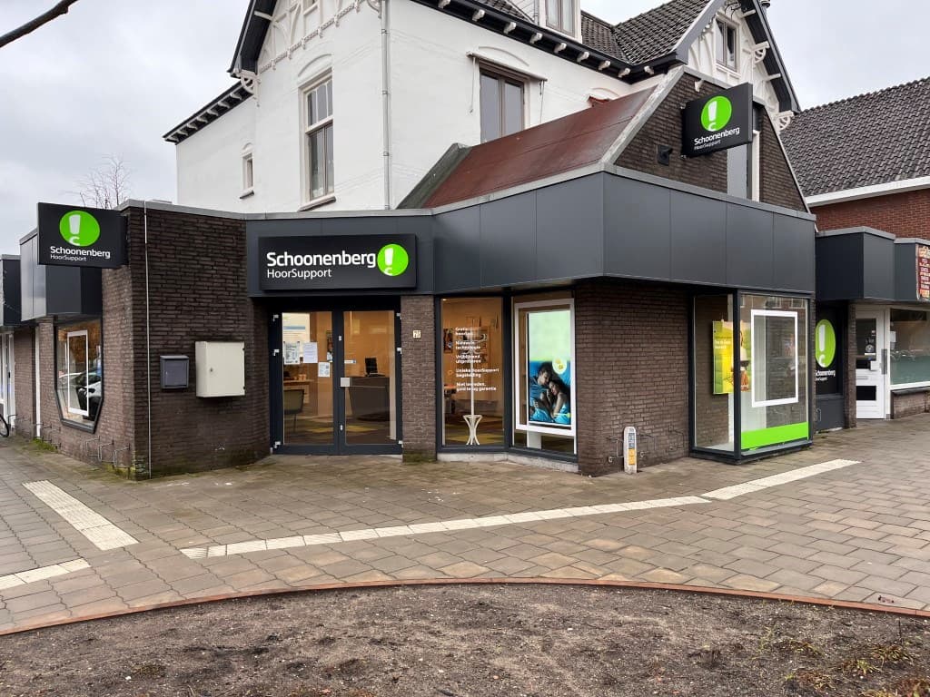 Appartement met moderne gevel en grote ramen, gelegen aan een straat met stenen bestrating en een parkje in de nabijheid