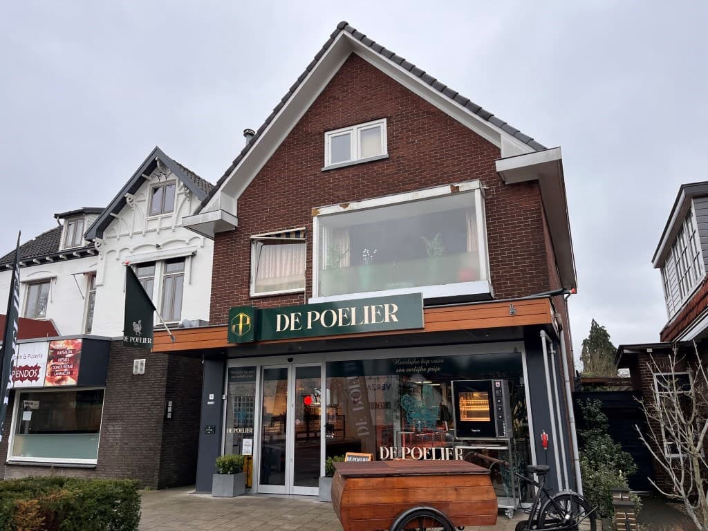Appartementsgebouw met winkel op de begane grond, gevel in baksteen en houten elementen, grijze lucht boven het pand