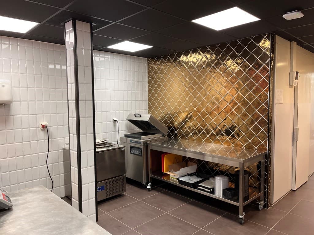Moderne keuken met roestvrijstalen werkbladen, tegels en een gasfornuis met een afzuigkap.
