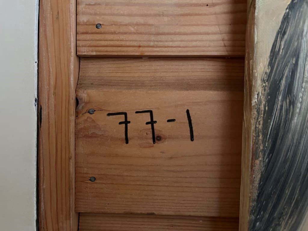 Houten wand met duidelijk zichtbaar nummer 77-1 geschreven in zwarte cijfers