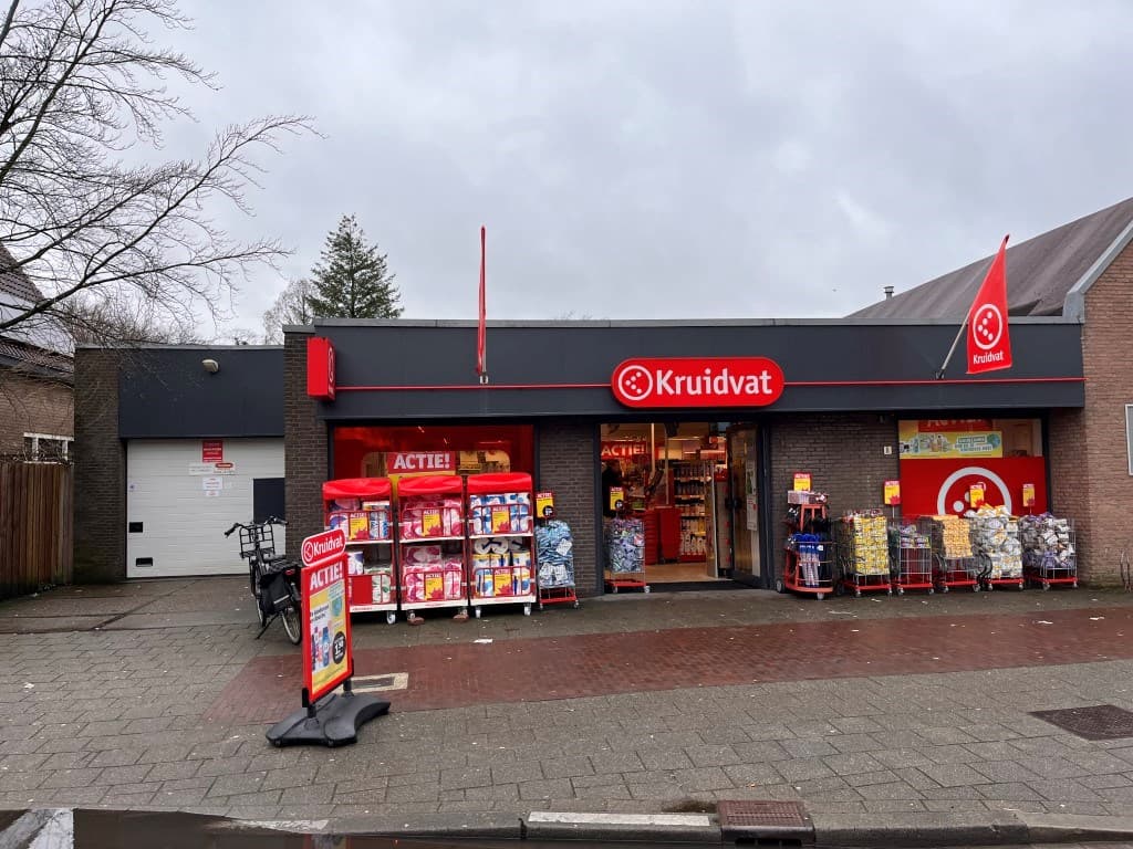 Kruidvat winkel met rode en gele displays en een stoep met diverse producten voor de ingang