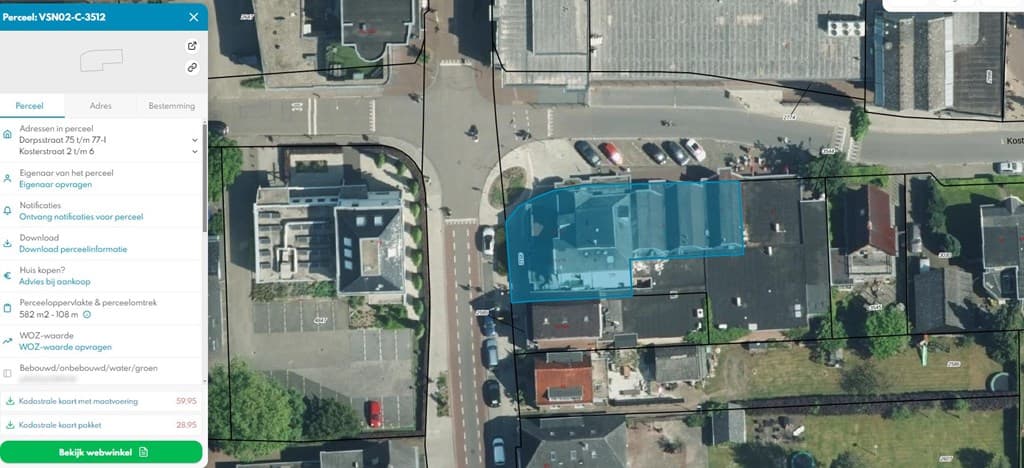 Bovenaanzicht van een appartement gelegen aan een kruising met omliggende gebouwen en aparte parkeerplaatsen.