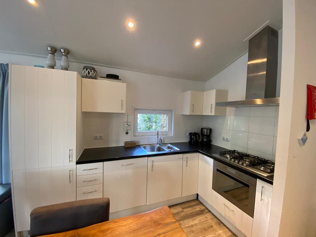 Moderne keuken met witte kasten, zwarte werkblad, kookplaat, oven en venster met uitzicht naar buiten