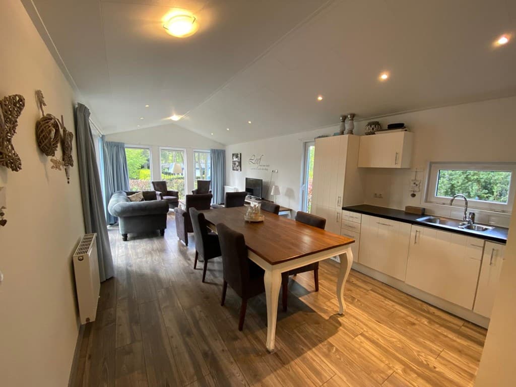 Moderne open woonkamer met eetruimte, keuken en toegang tot de tuin met veel natuurlijk licht.