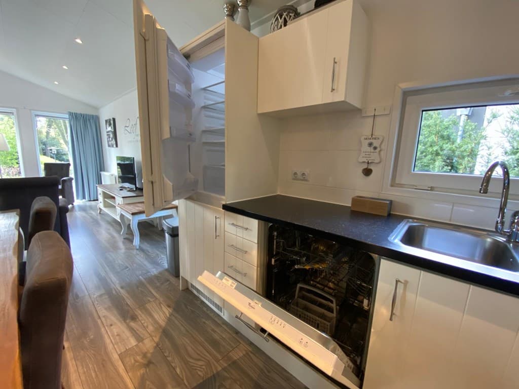 Keukeninrichting met open kast, koelkast, gootsteen en vaatwasser, in lichte kleuren met modern design en houten vloer