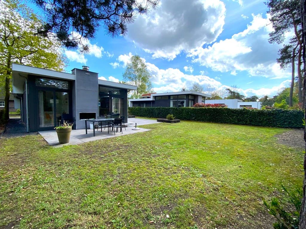 Moderne vakantiewoning met patio, grasveld en omgeving van bomen op EuroParcs De Achterhoek in Lochem