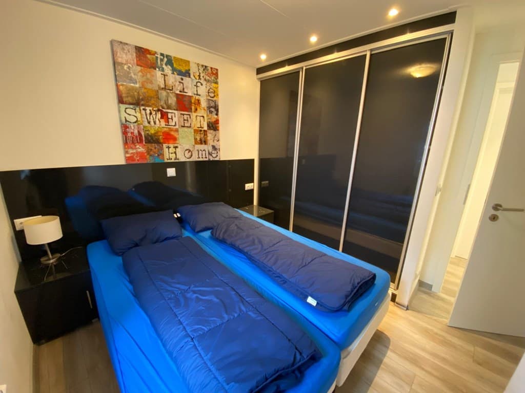 Slaapkamer met twee aparte bedden, moderne kast, en kleurrijk kunstwerk aan de muur.