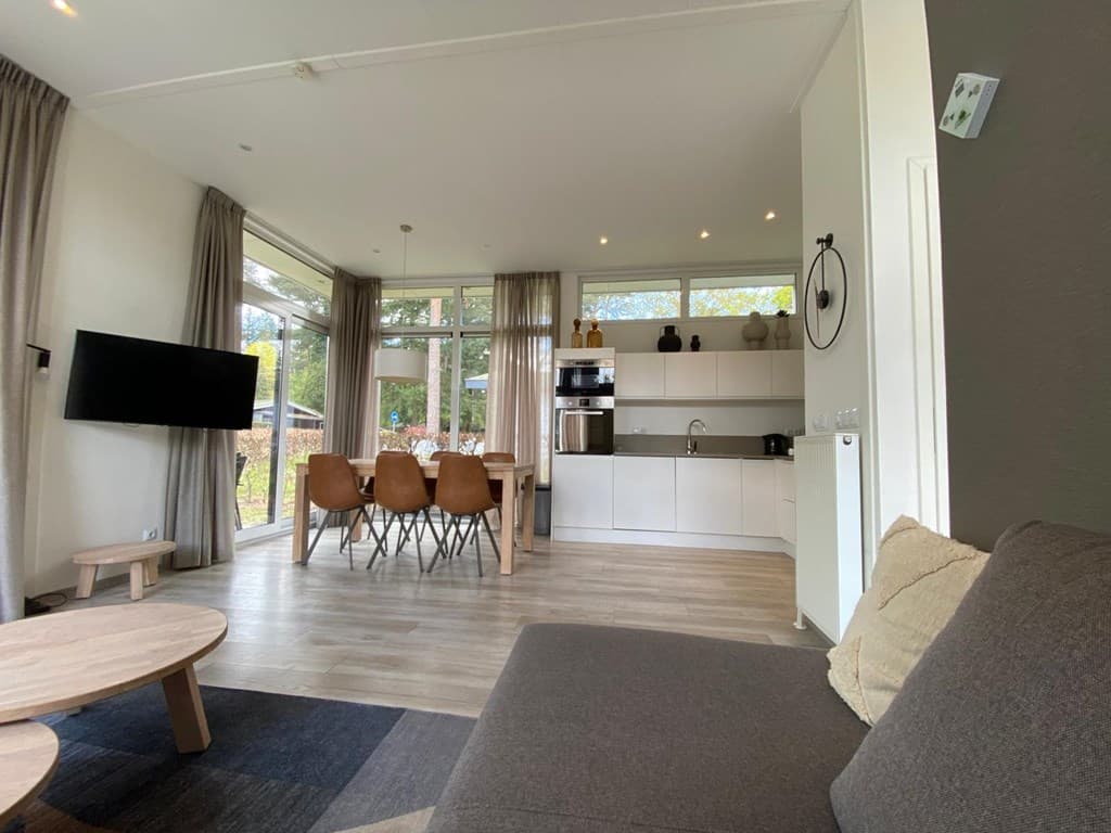 Moderne woning met open keuken en eetgedeelte, grote ramen en comfortabele zithoek met bank en salontafel