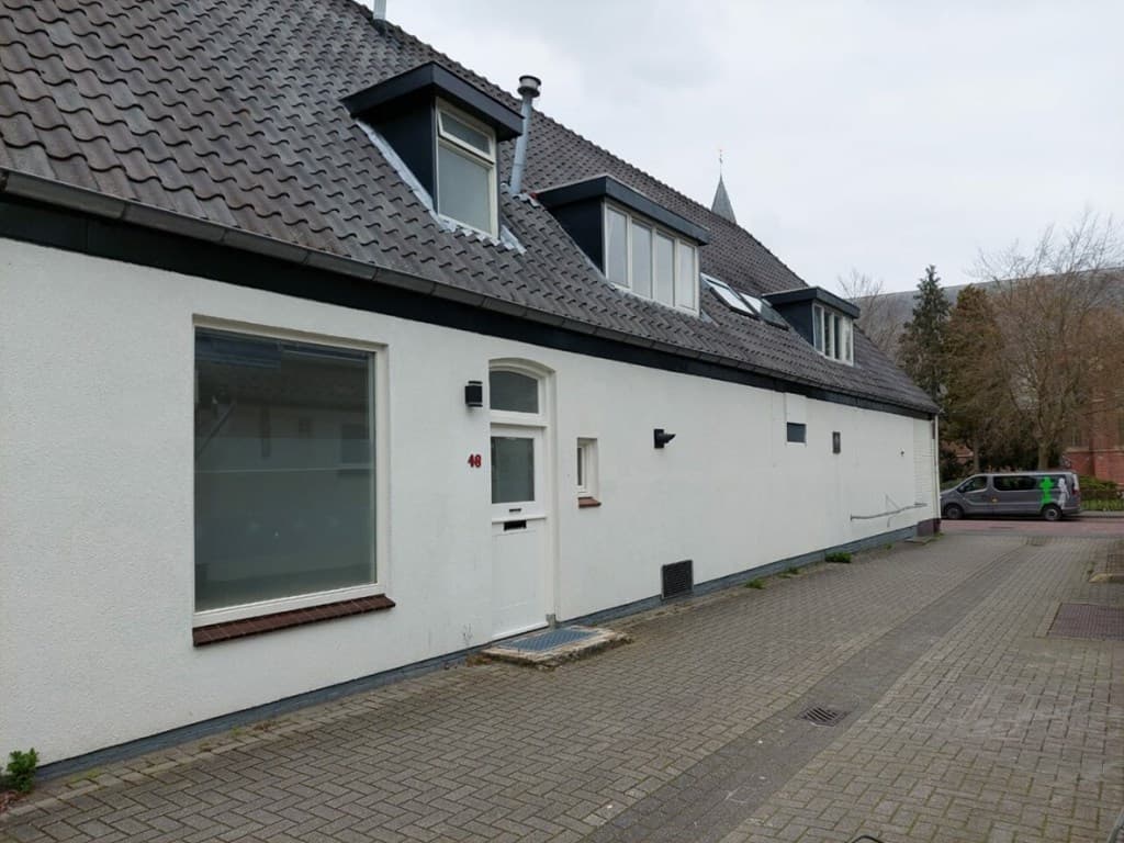 Woning met een lichte gevel, moderne dakramen en een betegeld pad voor de deur