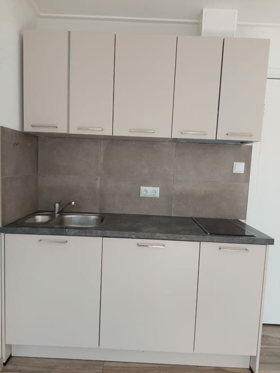 Keuken met wandkast, spoelbak en aanrechtblad in neutrale kleuren en keramische tegels op de muur