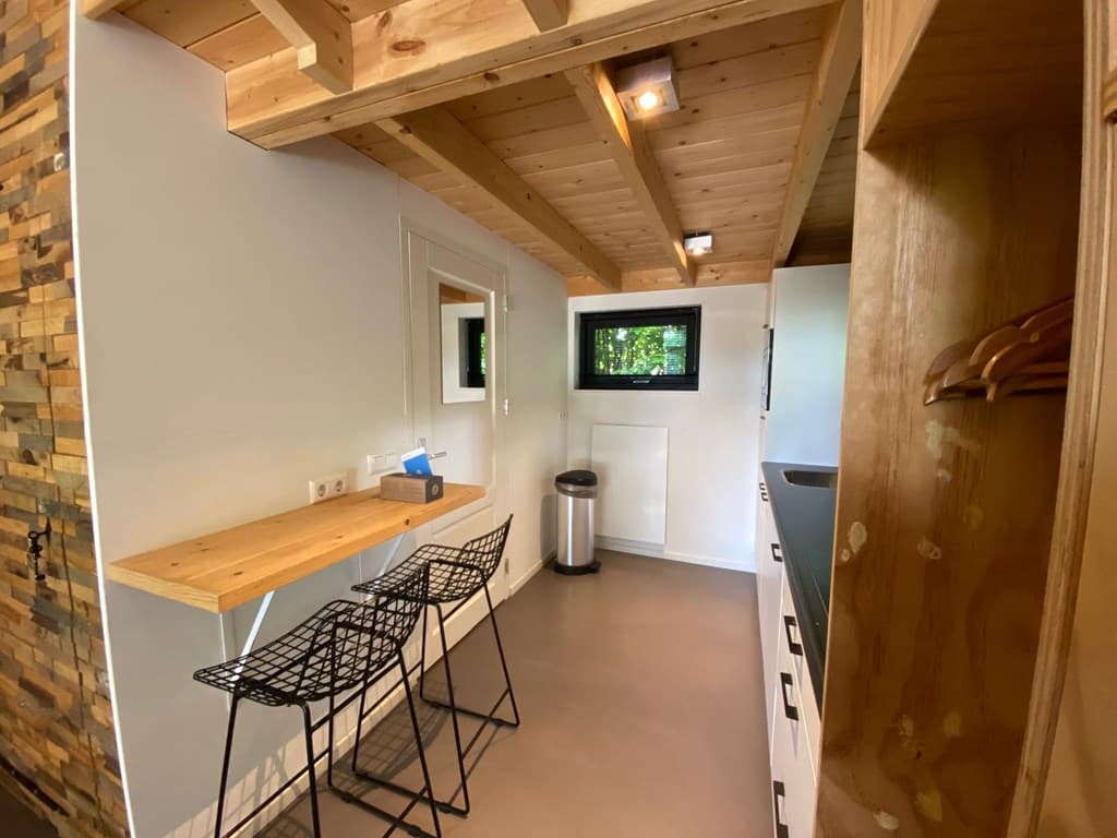 Keuken met houten plafond, eethoek met twee stoelen en een raam met uitzicht op de groene omgeving.