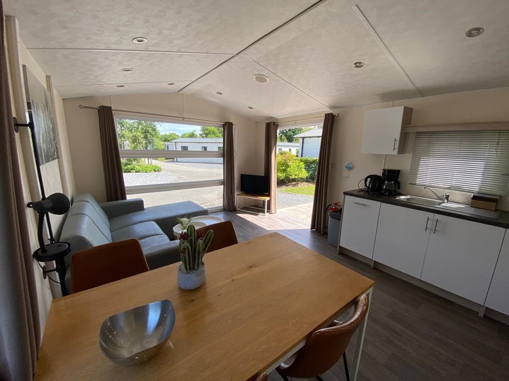 Zithoek met bank en tafel, open keuken met basisapparatuur en uitzicht op de buitenruimte bij EuroParcs Zuiderzee