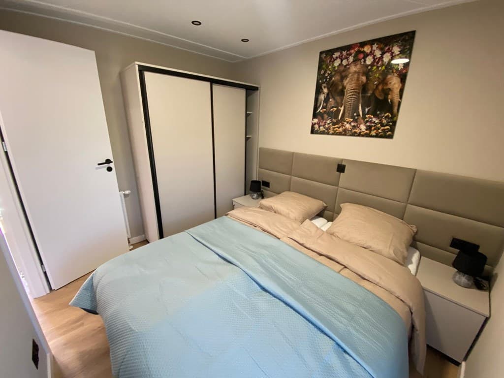 Slaapkamer met tweepersoonsbed, kast, nachtkastjes en een groot kunstwerk aan de muur.