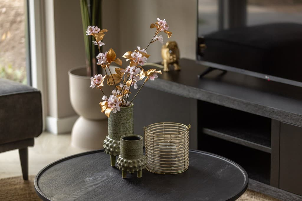 Decoratieve bloemen in vazen, een metalen kaarsenhouder en een tv-meubel met een tv in een moderne woonkamer