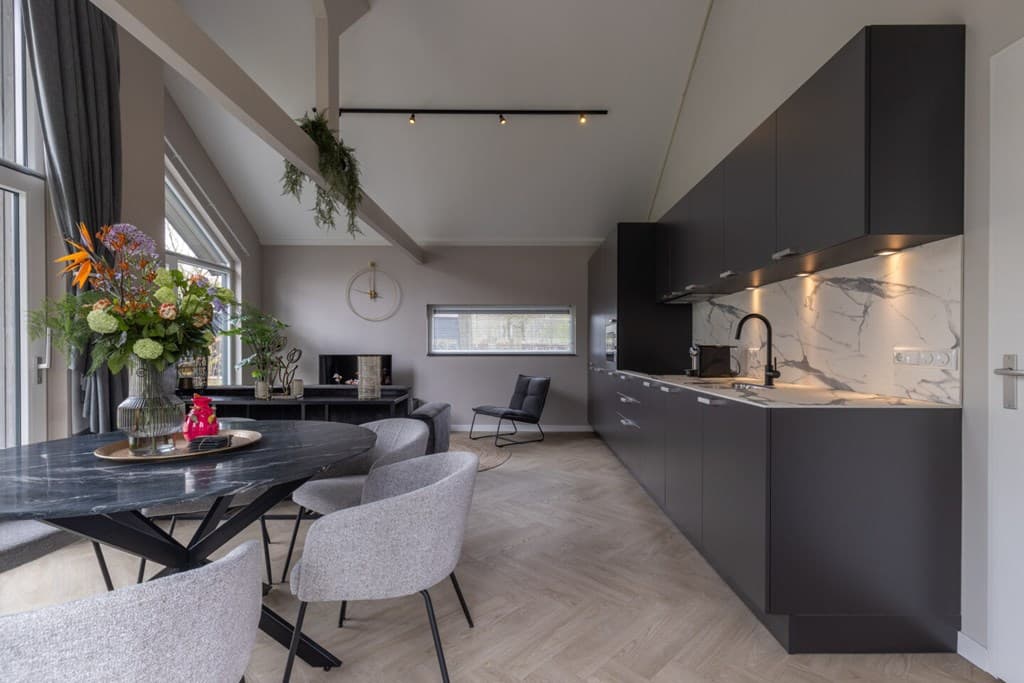 Moderne woonruimte met open keuken, een ronde eettafel en stijlvolle inrichting in neutrale kleuren.