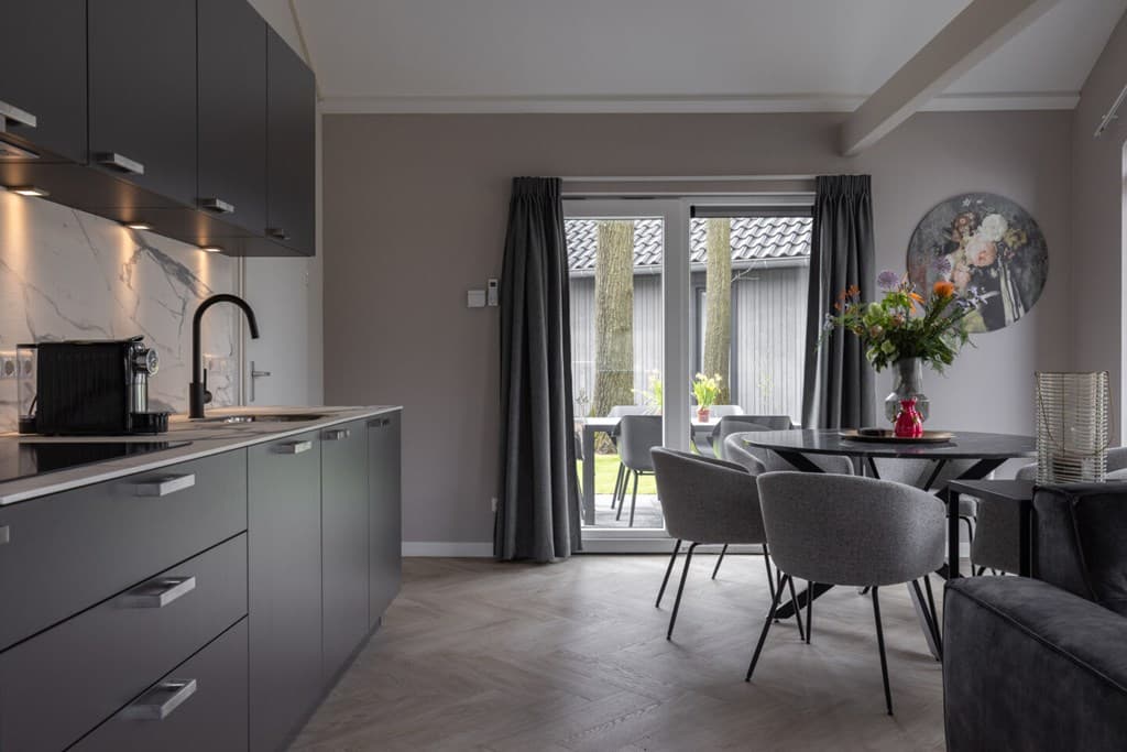 Zicht op moderne keuken en eetruimte met toegang tot een terras met uitzicht op groen in Vakantiepark Latour, Oirschot