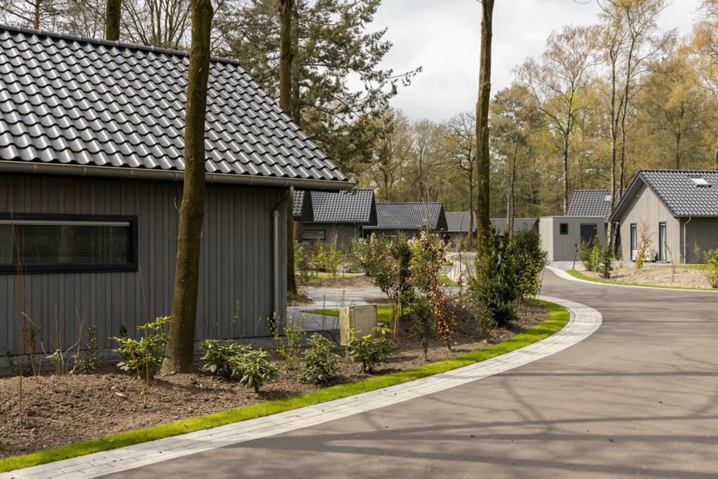 Moderne vakantiewoningen in een groene omgeving met bomen en een aangelegde oprit in Vakantiepark Latour, Oirschot