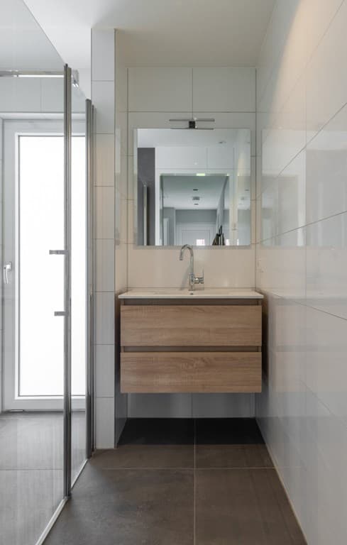 Moderne badkamer met wastafelmeubel van hout, spiegel en inloopdouche met glazen wand
