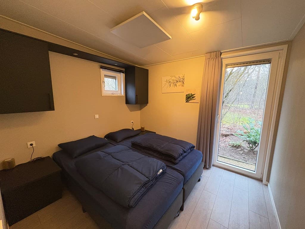 Slaapkamer met twee eenpersoonsbedden, raam met uitzicht op tuin en kast tegen de muur.