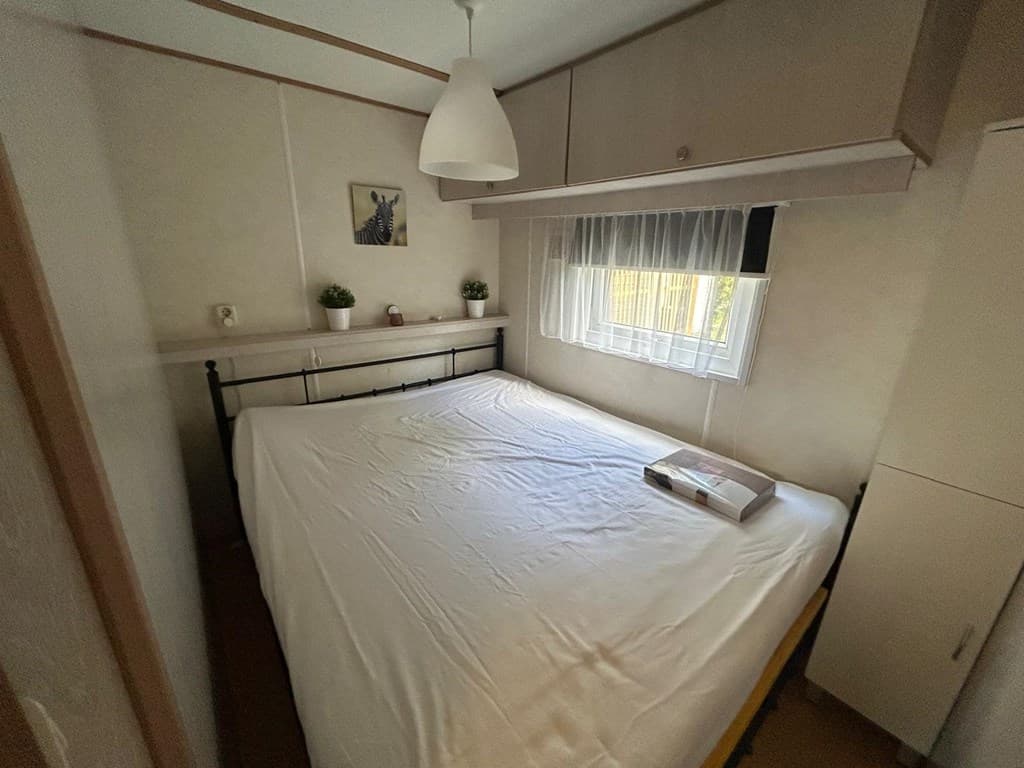 Slaapkamer met een bed, een kast, een raam met gordijnen en een decoratief element aan de muur.